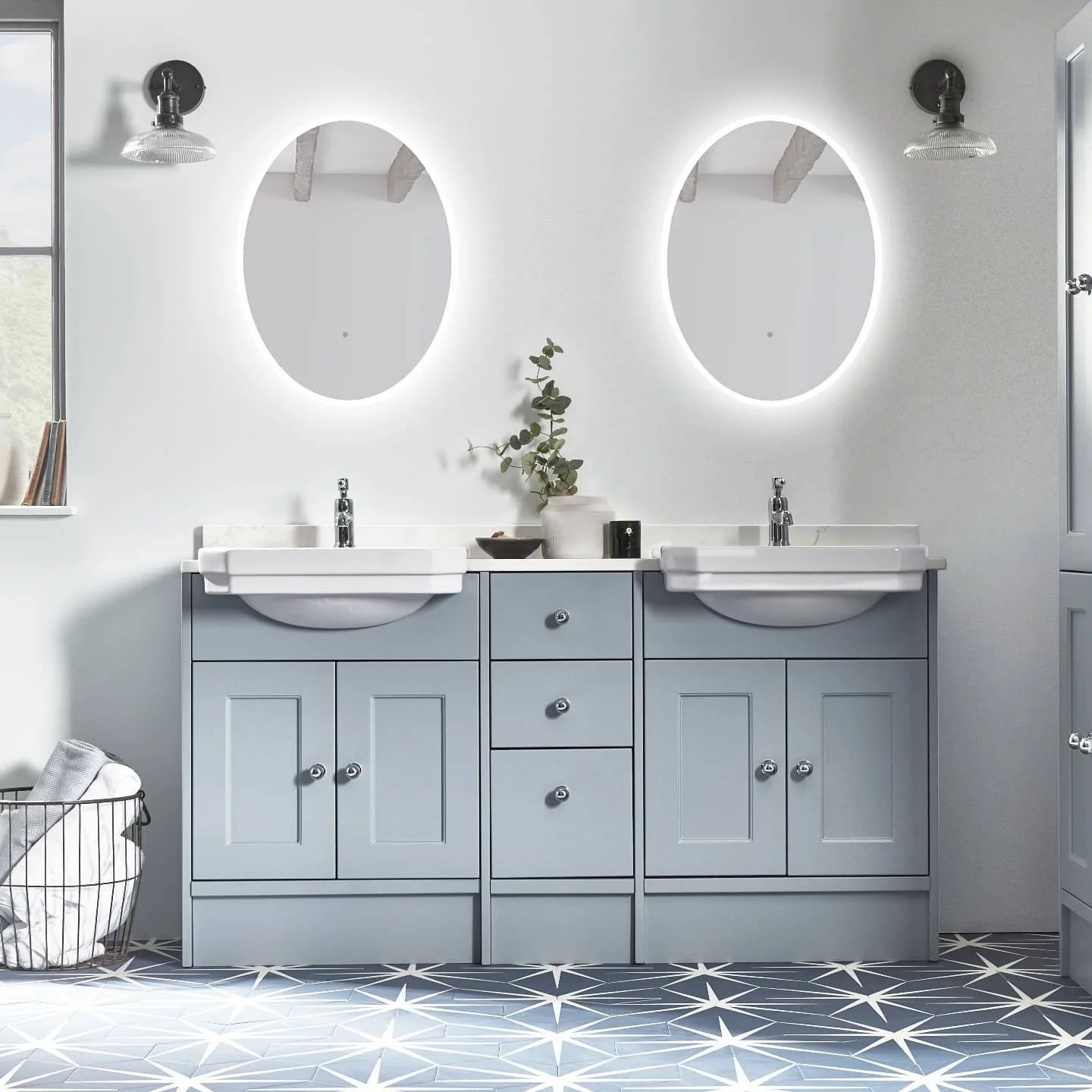 Double vanity bathroom with grey furniture, illuminated mirrors and patterned floor tiles.