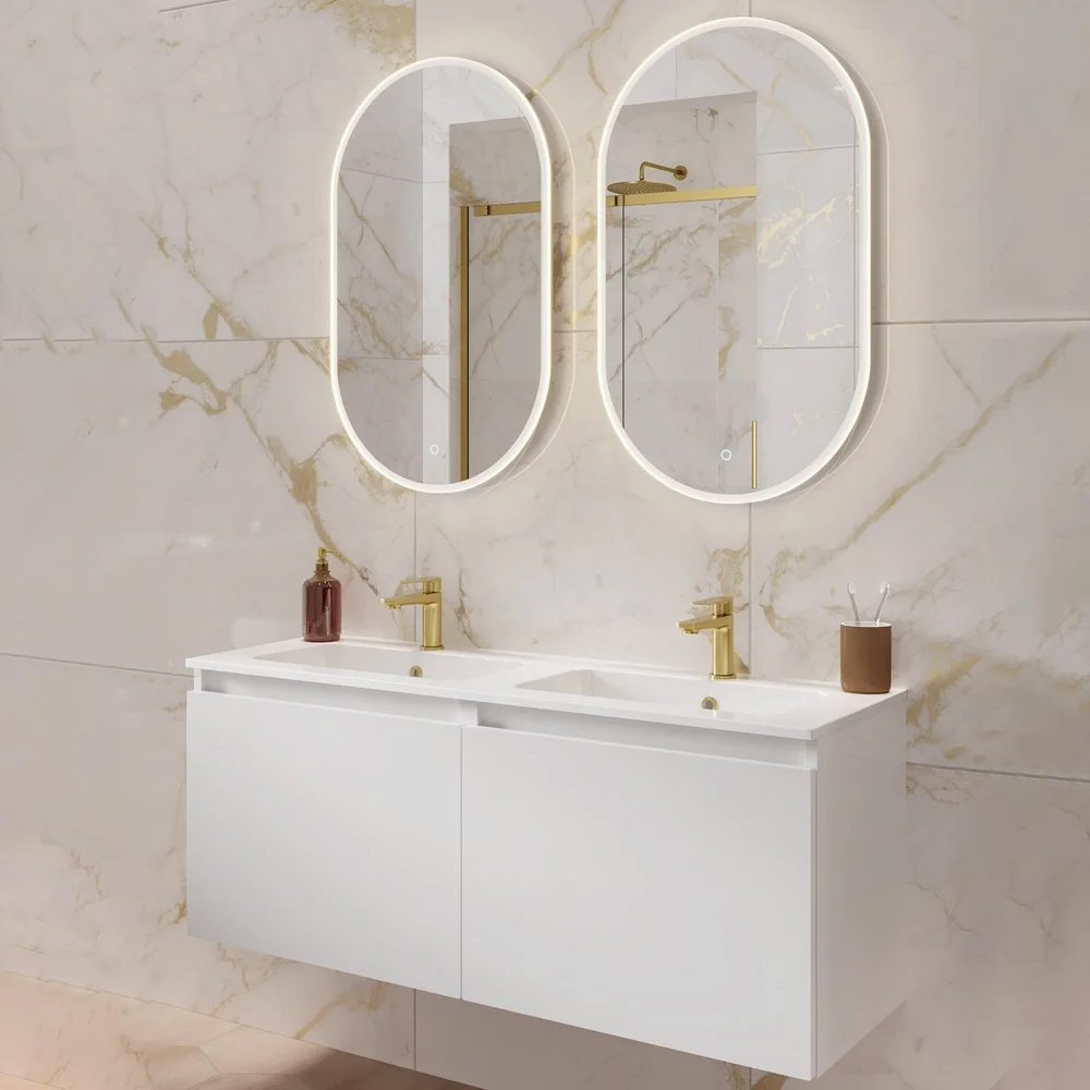 Phoenix white double wall-hung vanity unit with twin basins, brushed brass taps, illuminated LED mirrors, and marble-effect wall tiles.
